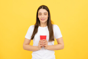 Emotion of young beautiful woman drink hot coffee, beauty face natural makeup, isolated over yellow background.