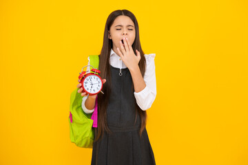Back to school. Teenager schoolgirl with bag hold clock alarm, time to learn. School children on isolated yellow background. Tired and bored teenager girl.