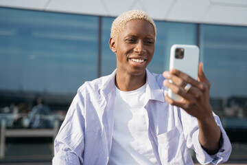 Authentic portrait of handsome smiling African American man using mobile phone communication,...