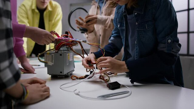 Kids with teacher working together on project with electric toys and robots at robotics classroom