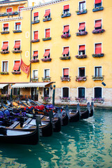 Fototapeta na wymiar Row of gandole near colorful house in Venice, Italy