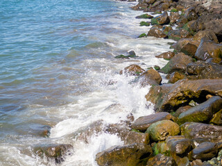 Surf. Waves crash on big rocks. Rocky coast and wave. Powerful coastline. Sea foam. The excitement of the sea. Huge coastal rocks.