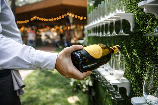 The waiter pours champagne into a glass - Powered by Adobe