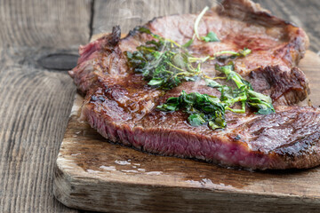 Fried beef steak with herbs on wooden board