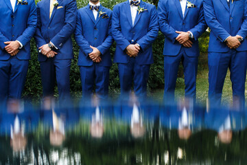 The groomsman in blue suits stand in a row