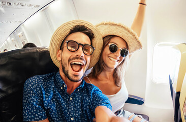 Fototapeta Happy tourist taking selfie inside airplane - Cheerful couple on summer vacation - Passengers boarding on plane - Holidays and transportation concept obraz