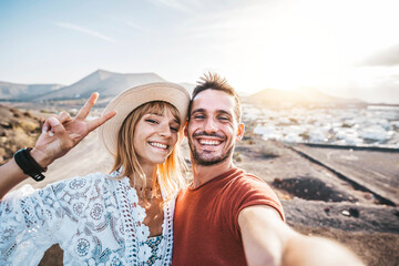 Happy couple taking selfie outside on vacation - Beautiful boyfriend and girlfriend having fun on summer holiday - obrazy, fototapety, plakaty