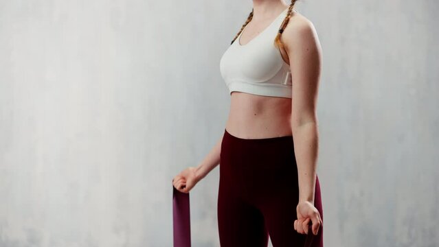 Sports woman in fashion sportswear exercising with elastic band stretch over greay background.