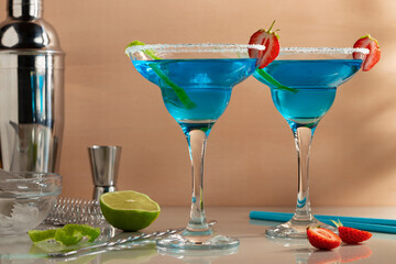 Fresh homemade blue margarita cocktail garnished with lime zest and strawberries, selective focus