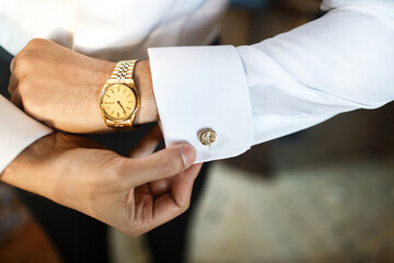 The groom fastens his cufflink at the wedding gathering