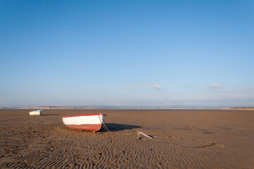 boats on a beach during a sunny day at low tide