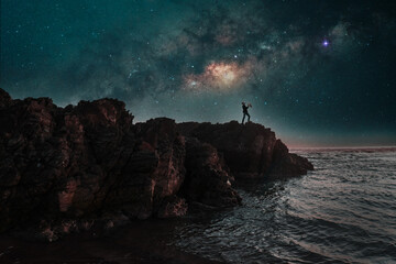 silhouette of a saxophonist playing on a cliff at night with the milky way in the background