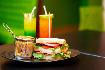 close up image of sliced bread with vegetables, fried potatoes, and glass of cocktail bit burred at the background