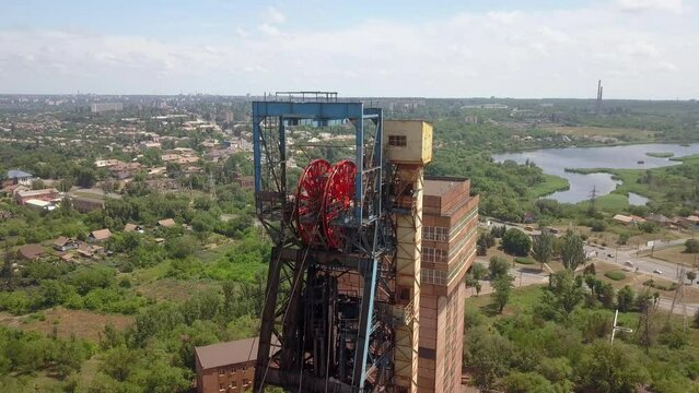 Headframe. Iron ore mining in the city center. Red mine in the city. Extraction of jelly ore by underground method. Drone aerial high angle view panning