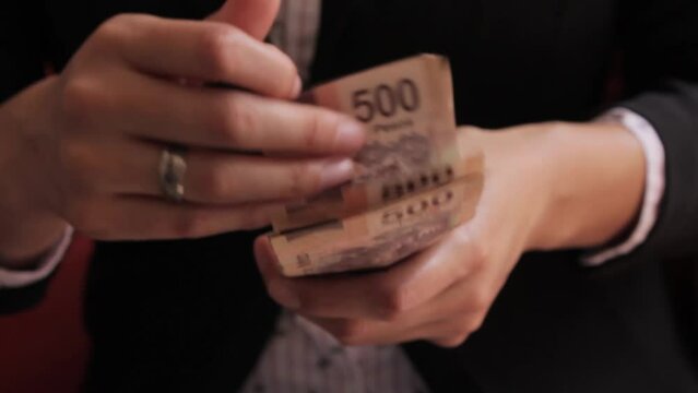 Manos de mujer contando dinero en billetes de quinientos pesos mexicanos