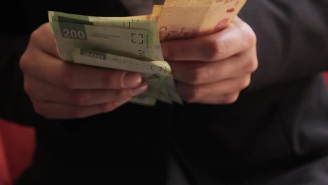 Manos de mujer contando dinero en billetes de docientos y cien pesos mexicanos