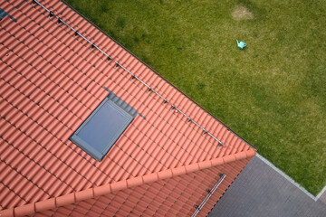 Closeup of attic window on house roof top covered with ceramic shingles. Tiled covering of building