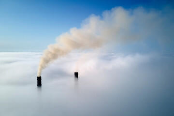 Obraz premium Coal power plant high pipes with black smoke moving upwards over clouds polluting atmosphere. Production of electrical energy with fossil fuel concept