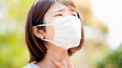 屋外で咳をするマスク姿のビジネスウーマン