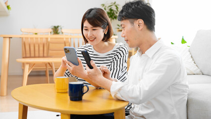 部屋でスマートフォンを操作する男性と女性