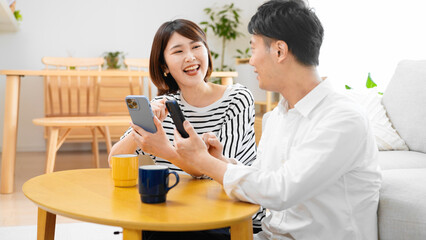 部屋でスマートフォンを操作する男性と女性