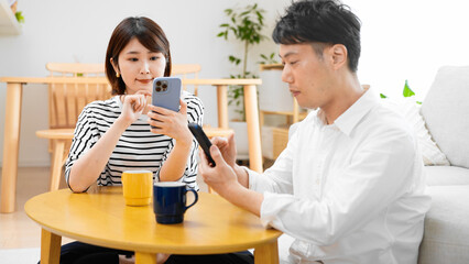 部屋でスマートフォンを操作する男性と女性