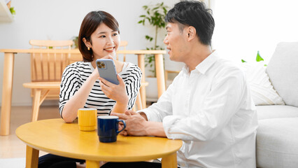 部屋でスマートフォンで調べ物をする男性と女性
