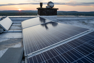 Solar panels located on the roof of the block. Green energy in modern city.  Sunset in the background