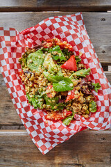 Top view of lentil salad with fresh greens and vegetables on a wooden picnic table