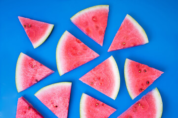 Juicy watermelon sliced into triangles. Top view of  fresh watermelon snaks lying on a blue background.
