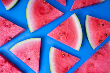Juicy watermelon sliced into triangles. Top view of  fresh watermelon snaks lying on a blue background.
