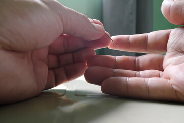 Selective focus of human hand popping or poking a blister with needle. Blisters care and lancing...