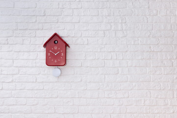 Red cuckoo clock on white brick wall	