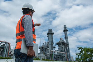 Engineer working and hand hold laptop at Power plant. People in PPE on Power plant construction.