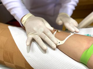 A nurse is collecting a blood sample, using a needle to puncture the vein to give the patient a saline solution.