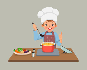 cute little boy chef cooking delicious vegetable soup showing thumb up