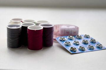 sewing kit thread needles pins and measuring tape on the table