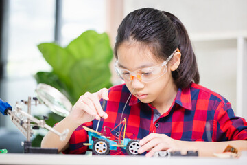 Child girl student build robotic cars, kid learning programming robot vehicles