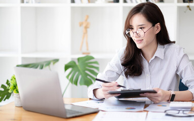 Obraz na płótnie Canvas Smiling asian business woman sitting in a modern office.