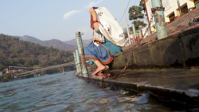 isolated young indian girl sitting at ganges river bank from different angle