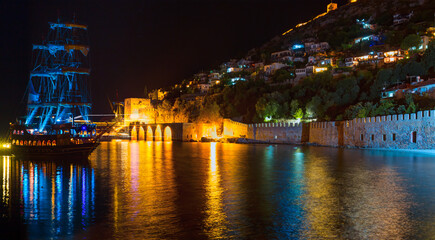 Fototapeta na wymiar A pirate tourist ship at anchor near ancient shipyard at night - Alanya, Turkey