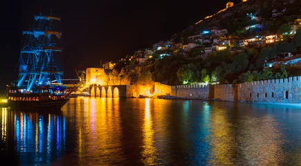 Foto op Plexiglas A pirate tourist ship at anchor near ancient shipyard at night - Alanya, Turkey © muratart