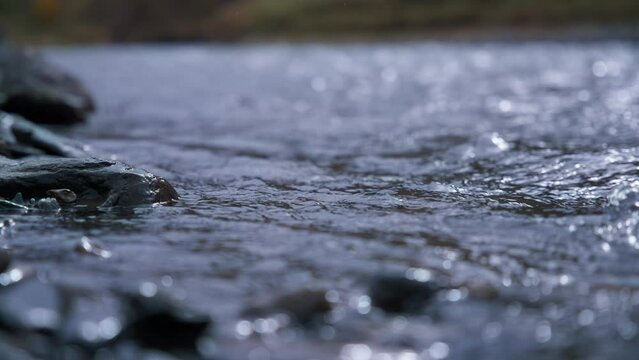 Mountain creek water stream running through stones. Slow motion. 