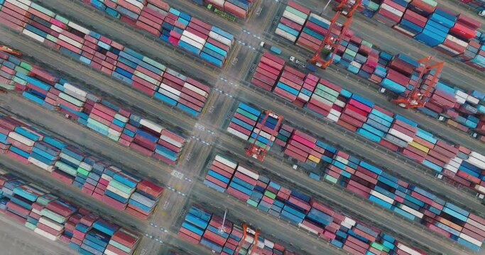 Aerial topdown view of shipping containers waiting on the docks to be loaded onto a container ship at container terminal port. import export and global supply chain concept.