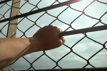 hand and fence on sky background [Concept of hurdles and hopes]