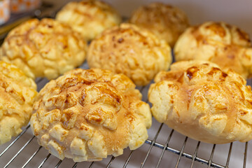 Freshly baked pineapple bun in bakery store shelf. A pineapple bun is a kind of sweet bun...