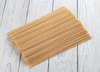 Uncooked spaghetti pasta on white wooden background
