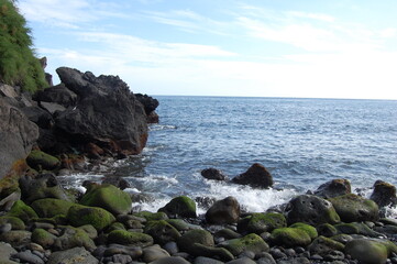 Fototapeta na wymiar stone beach with light waves and blue sky