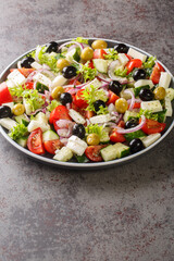 Healthy food Greek salad of fresh cucumber, tomato, sweet pepper, lettuce, red onion, feta cheese and olives with olive oil. Vertical