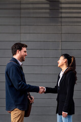 Fototapeta na wymiar caucasian businessman and asiatic businesswoman shaking hands, concept of entrepreneurship and business, copy space for text